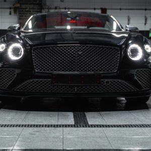 Front view of a sleek black Bentley inside a car wash, showcasing elegance and luxury.